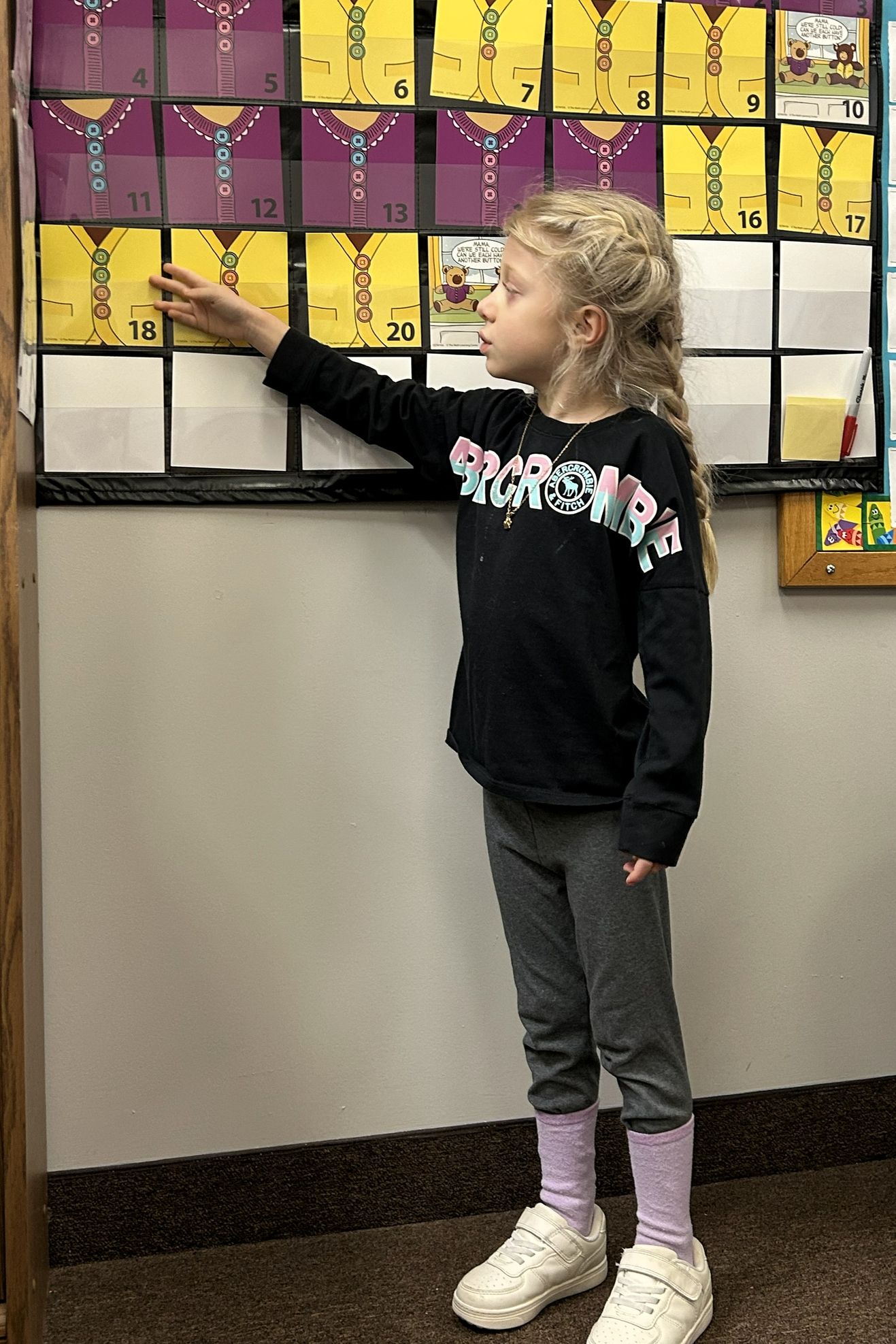 A student points to a number on a classroom counting chart during a math lesson.