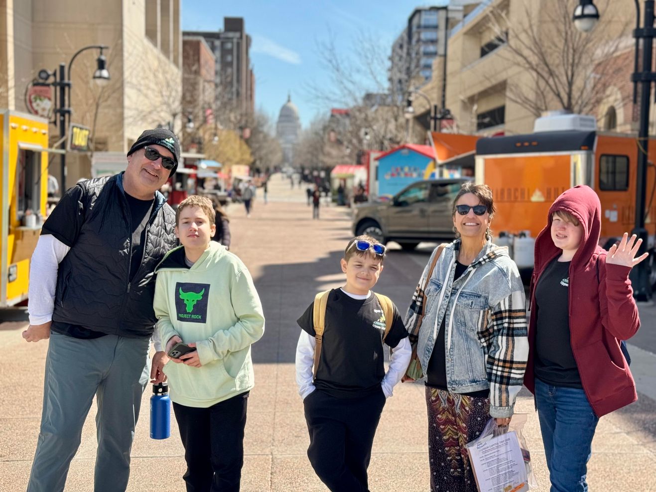 Students and a teacher pose on State Street in Madison, Wisconsin, with the State Capitol dome visible in the background.