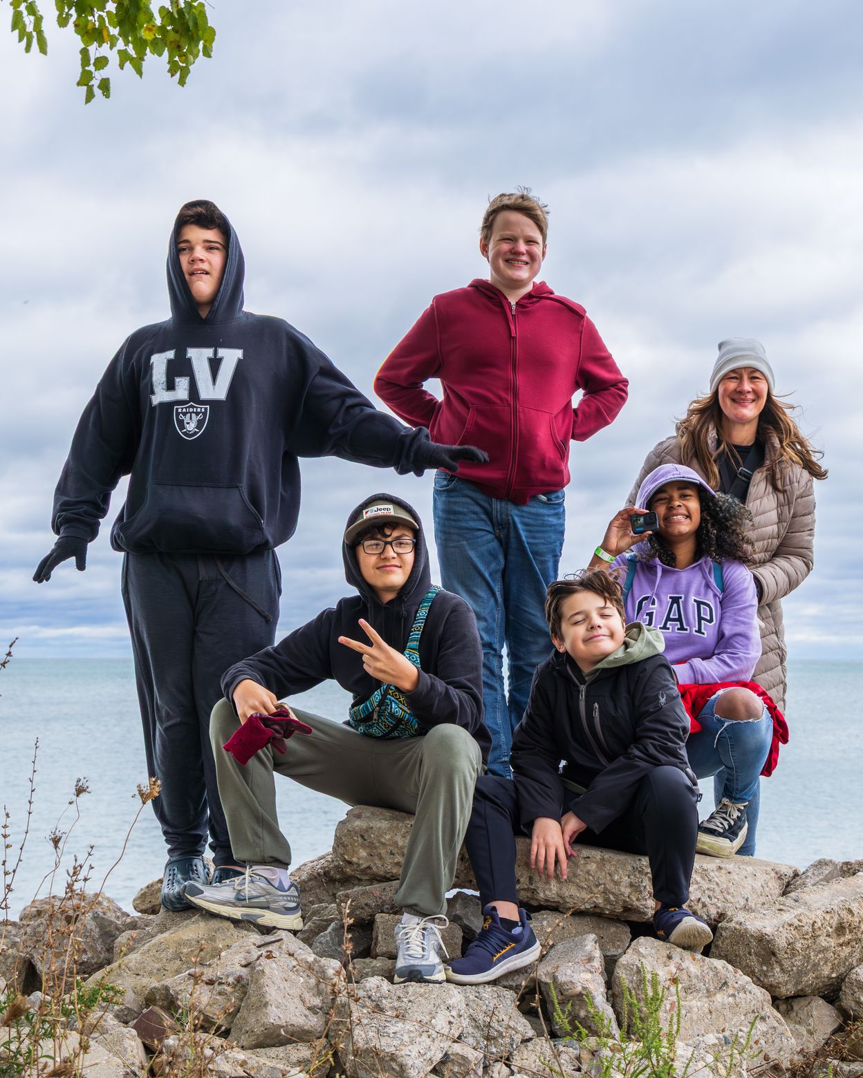 Five Open Wings students and a staff member on the rocky Lake Michigan shoreline, smiling together on an outing.